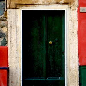Porte avec poignée en cuivre encadrée de pierres taillées sur mur vert et rouge - Italie  - collection de photos clin d'oeil, catégorie portes